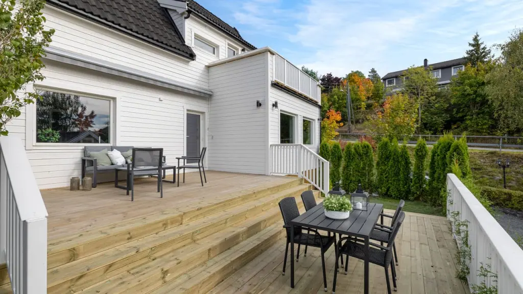 Bolig sett fra hagen, med terrasse og hvit kledning.