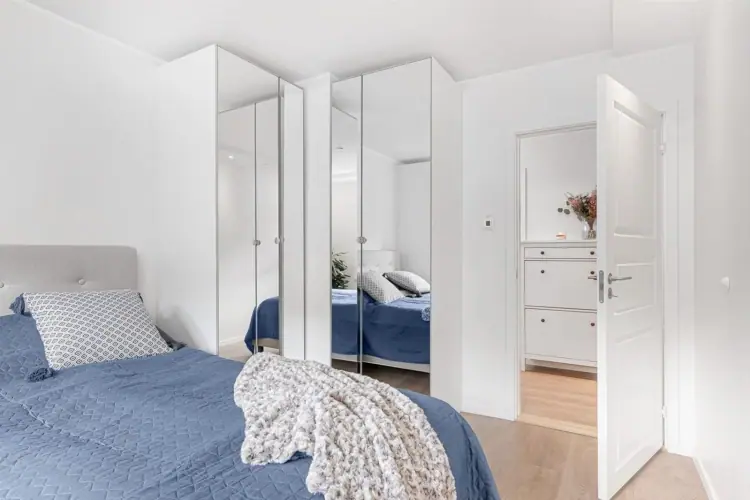 Soverom med speilgarderobe langs veggen og dør ut til gangen.